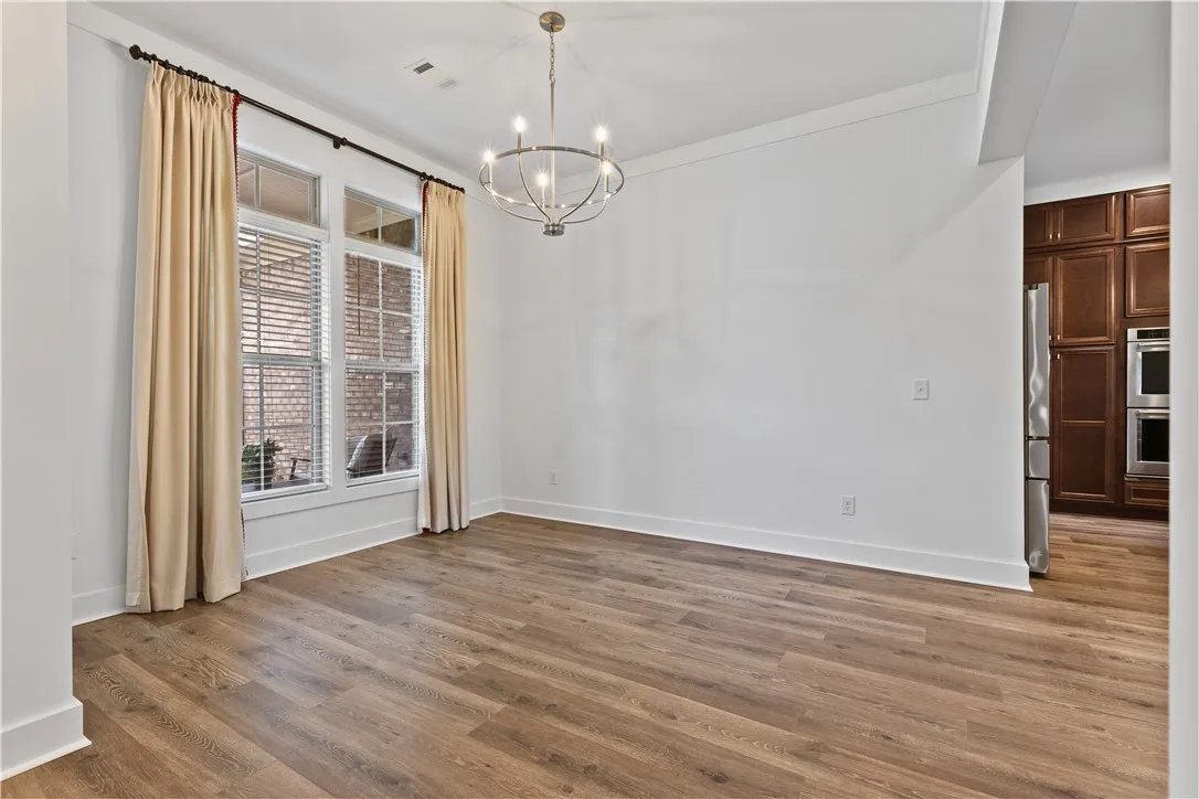 A well-lit interior space with rich flooring and a stylish overhead chandelier in the dining room.