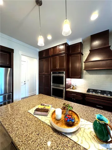 View of the island with bar stool seating space, and view of hall entry from the garage and also leads to the laundry and bedroom 3 ensuite