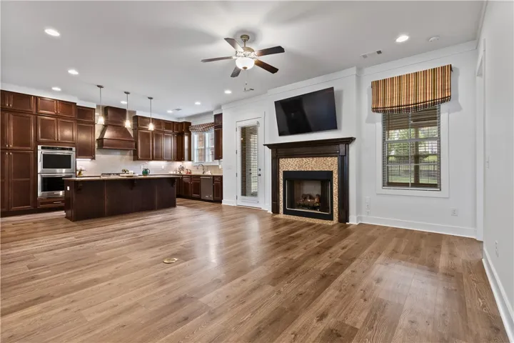 An open concept living area features a kitchen with a spacious island and a cozy fireplace with intricate tile work.