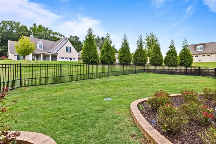 Well-maintained and manicured lawn with black aluminum fencing with a gate