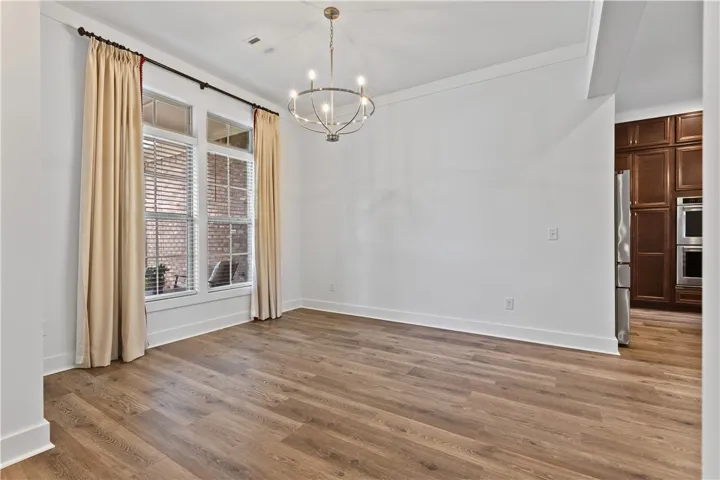 A well-lit interior space with rich flooring and a stylish overhead chandelier in the dining room.