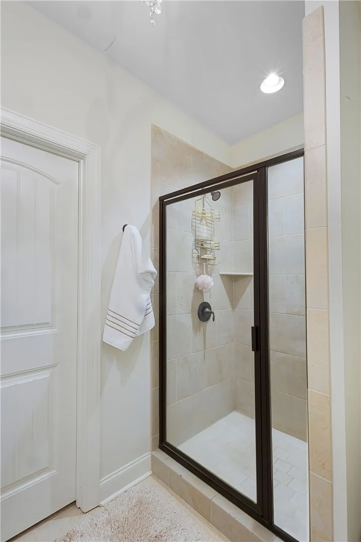 A glass-enclosed walk-in shower features neutral tile surrounds and integrated corner shelving.
