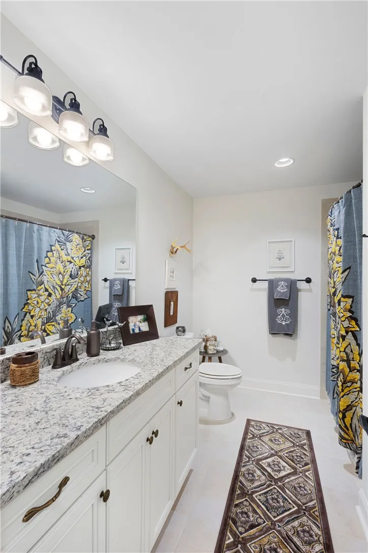 Polished stone counters and clean white cabinetry elevate this inviting secondary bath.