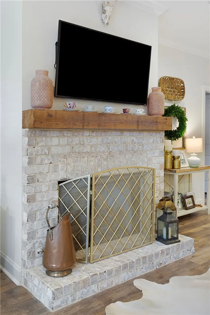 A brick fireplace with a rustic wood mantel serves as a handsome living room focal point.