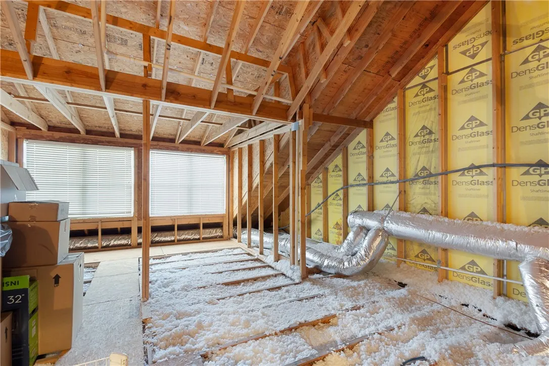 An unfinished upper level space reveals exposed wood framing and insulation details.