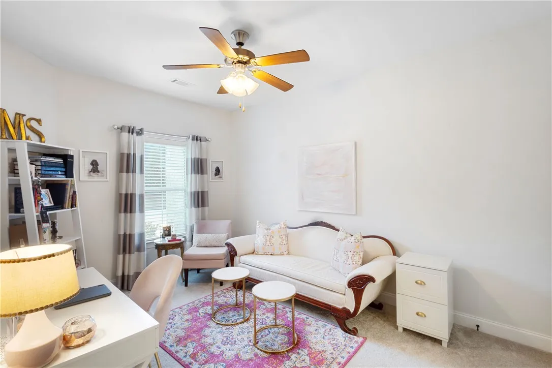 Plentiful natural light fills a versatile space featuring clean white walls and soft carpet flooring.