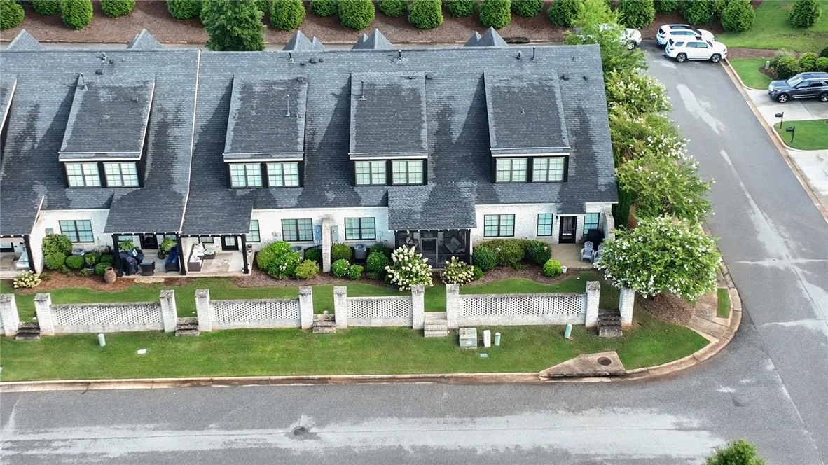 Elegant brick townhomes feature classic architecture with dark shingled roofs and privacy wall.