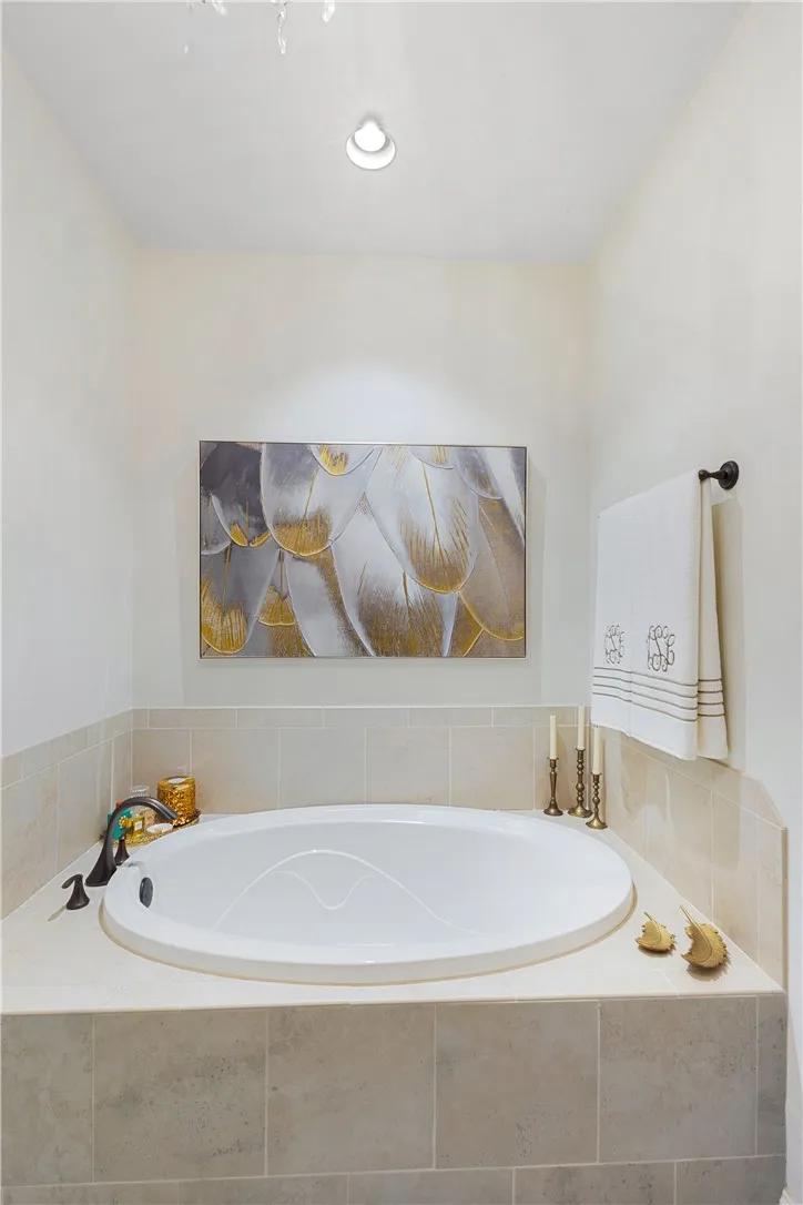 A deep soaking tub is framed by elegant tile surround and warm recessed lighting.