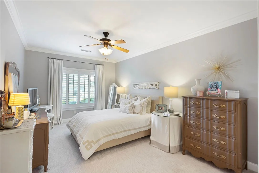 Elegant crown molding and plush patterned carpeting define this serene, comfortable sleeping space.
