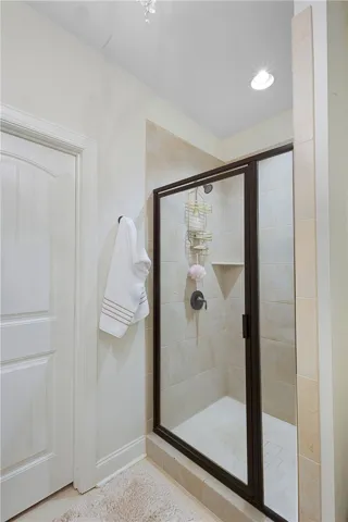 A glass-enclosed walk-in shower features neutral tile surrounds and integrated corner shelving.