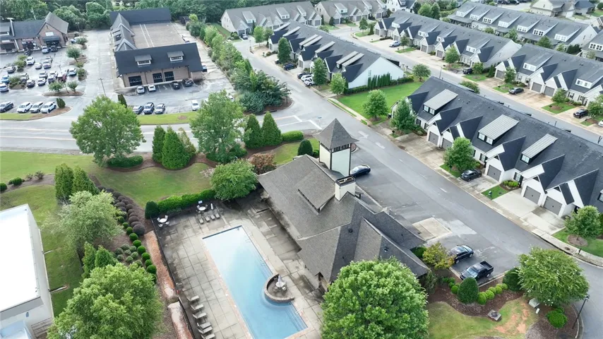 An aerial perspective showcases the community pool alongside the neighborhood clubhouse and surrounding townhomes.