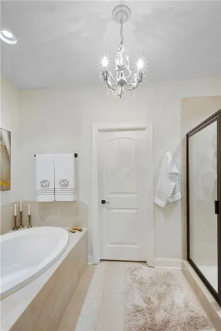 A classic chandelier illuminates the spacious bathing area featuring a deep soaking tub and tile floors.