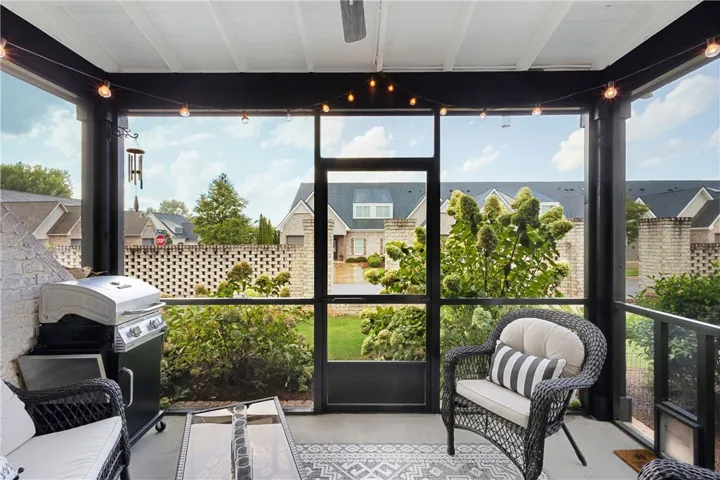 A screened porch overlooks the landscaped backyard and neighboring brick structures.