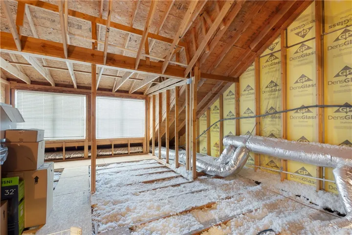 An unfinished upper level space reveals exposed wood framing and insulation details.