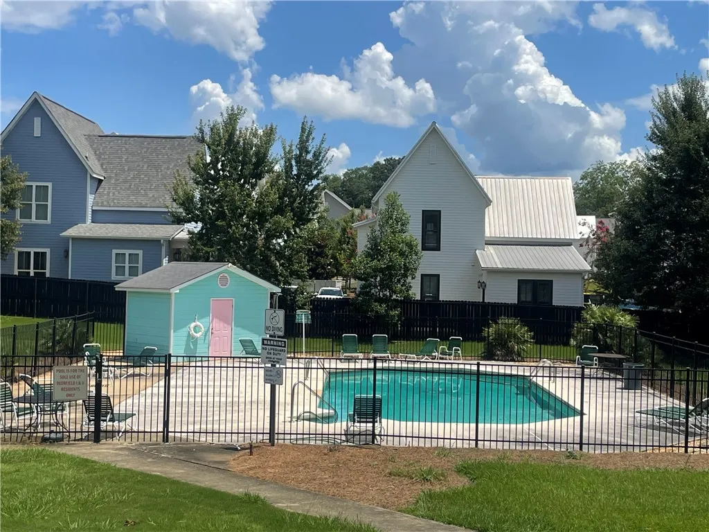 An inviting community pool area, enclosed by fencing, offers a refreshing escape amidst residential architecture.