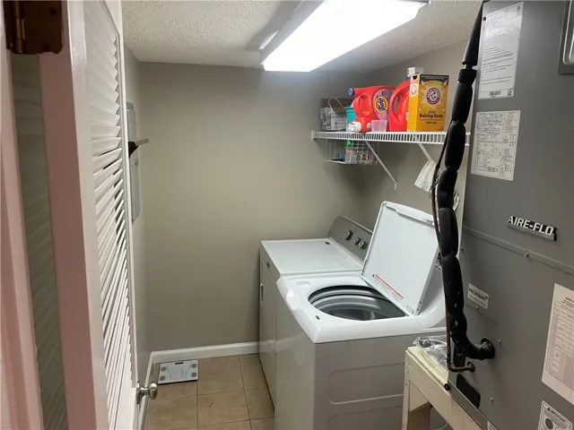 A well-appointed utility room features a washer, shelves, and tiled flooring.