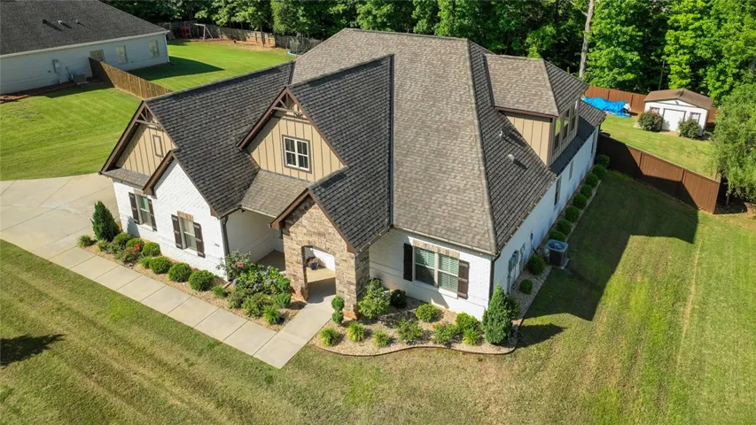 A striking home showcasing a blend of white brick and stone accents, complemented by an attached garage and well-maintained landscaping.