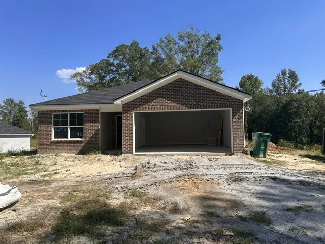 Classic brick exterior and an attached garage define this newly constructed home under a clear sky.
