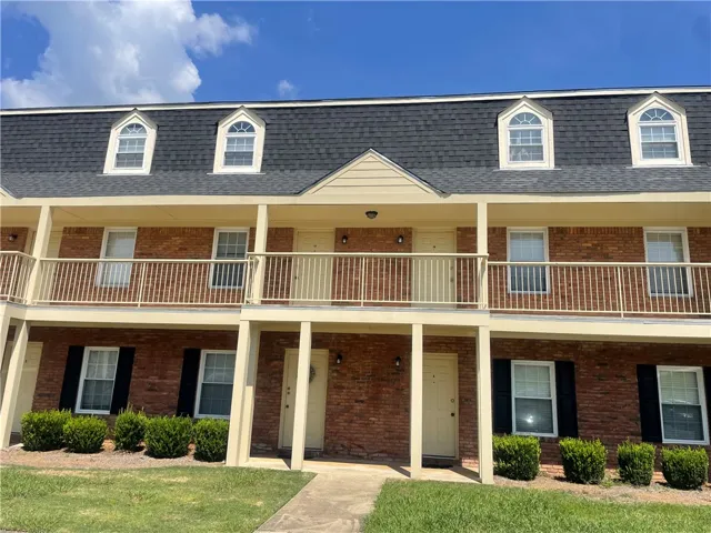 Classic brick architecture features symmetric dormers and private entrances under a clear blue sky.