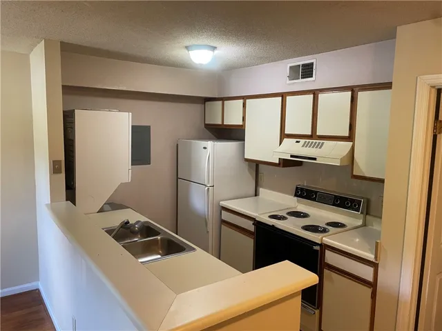 A functional kitchen features wood-trimmed cabinetry, durable laminate countertops, and a convenient breakfast bar setup.