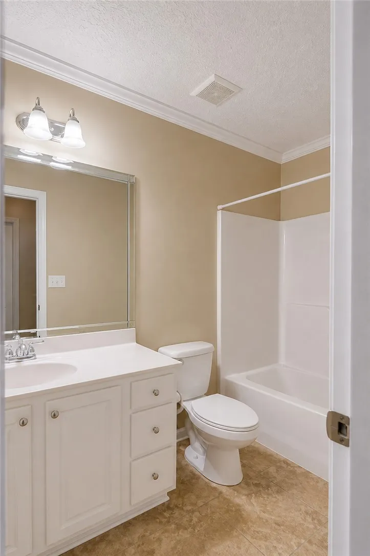 Functional full bathroom featuring a tub and shower combo, vanity with ample storage, and easy-care flooring.