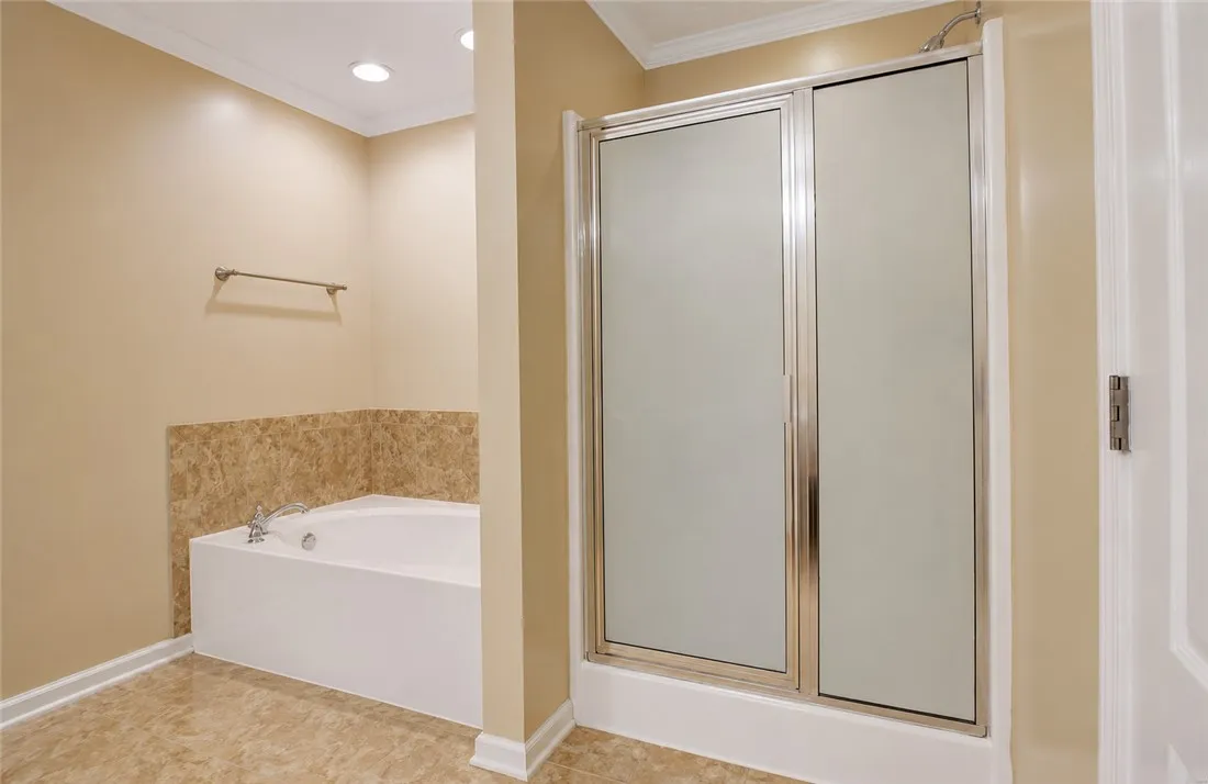 Indulge in relaxation with this inviting soaking tub and sleek glass-enclosed shower.
