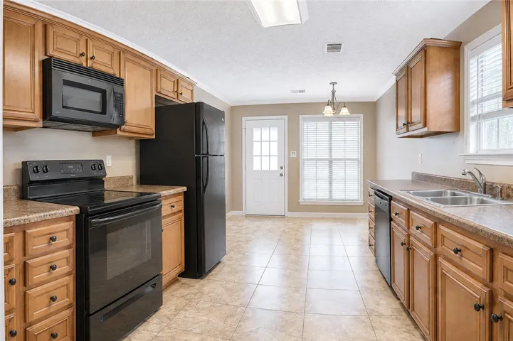 A well-appointed kitchen features black appliances, ample cabinetry, and durable tile flooring.