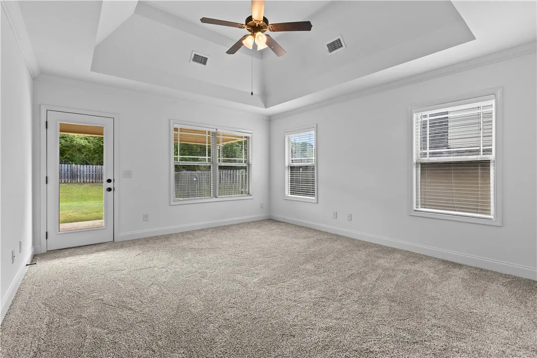 Spacious primary bedroom with a tray ceiling and new paint and carpet with direct access to the private back yard.