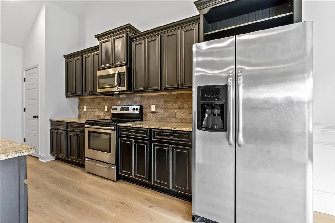 Dark cabinetry with good storage space, granite countertops,  stainless steel appliances, and bar seating/dining.