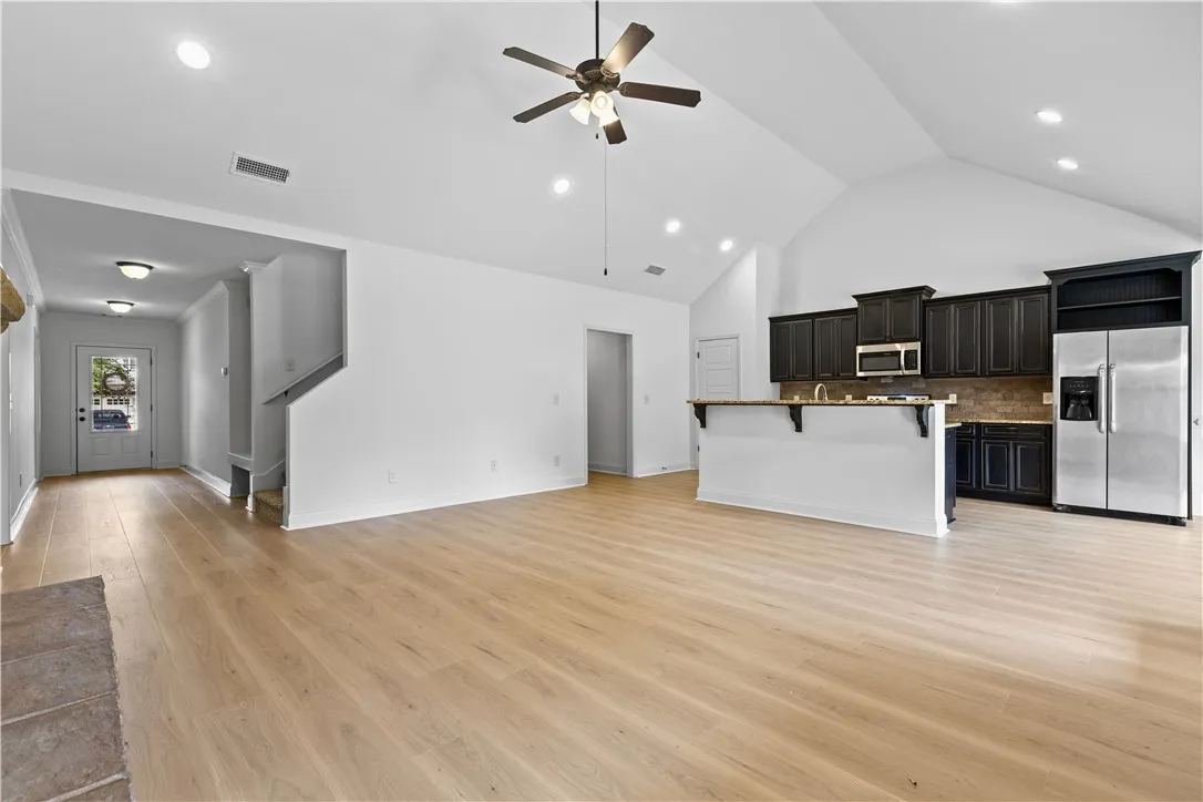 A vaulted ceiling living area transitions seamlessly into an open-concept kitchen with dark cabinetry.