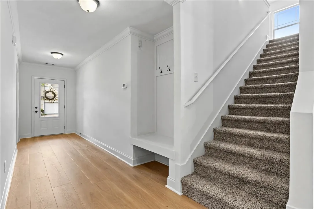A welcoming entryway shows off the new LVP flooring. Built-in hall tree/bench, new carpet on the stairs