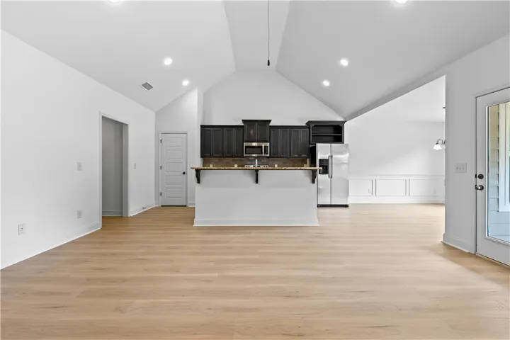 A well-lit, open-concept space features a vaulted ceiling and brand new LVP flooring