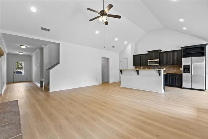 A vaulted ceiling living area transitions seamlessly into an open-concept kitchen with dark cabinetry.