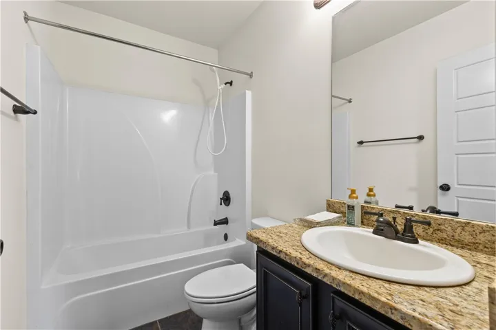 A second downstairs full bath features a  shower-tub combination and a vanity with a granite countertop.