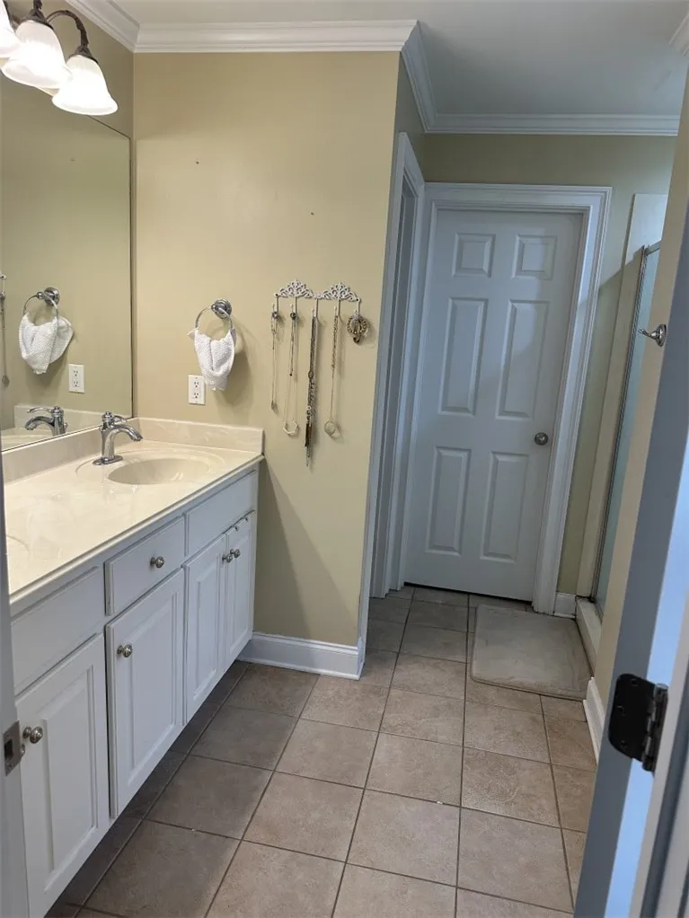 Crown molding and tiled floors elevate the classic design of this spacious master bathroom.