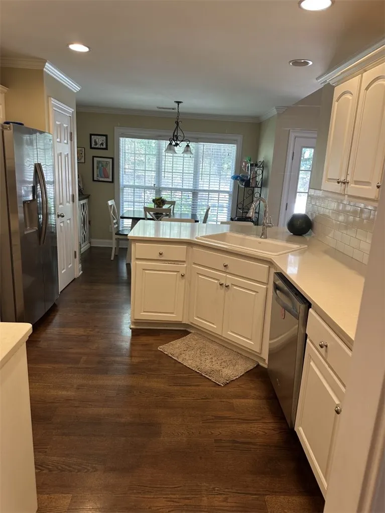 Rich wood flooring anchors this kitchen featuring clean countertops and classic crown molding details.