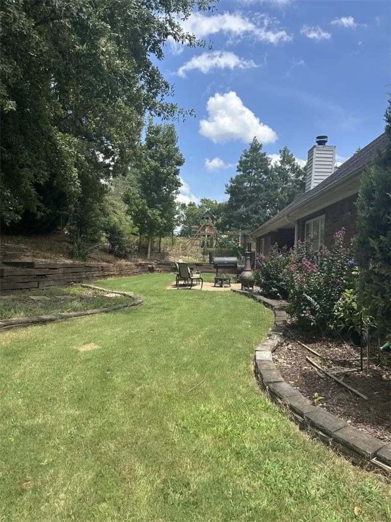 Mature trees line a curved lawn and brick exterior under blue skies.