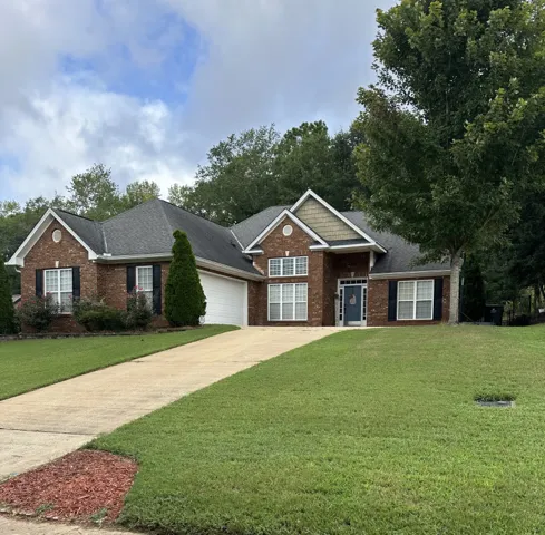 Classic brick elevation highlights this multi-gabled residence with a long concrete driveway.