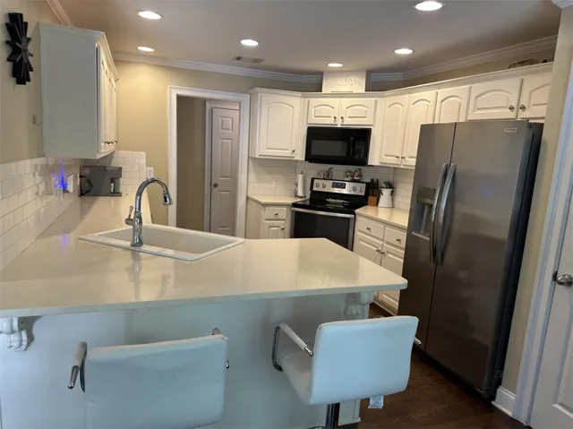 Elegant crown molding complements the sleek stone countertops and classic cabinetry in this kitchen.