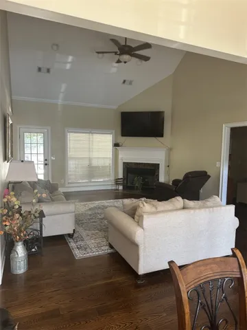 Rich hardwood floors complement the vaulted ceiling and central fireplace in this inviting living space.