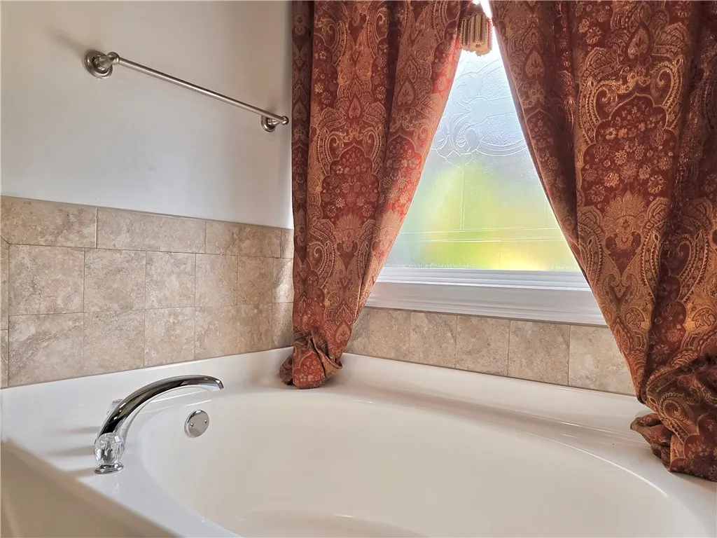 Tiled walls and a frosted window surround this deep, relaxing bathtub.
