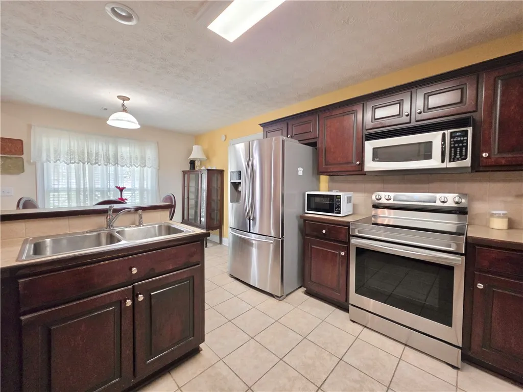 Rich dark wood cabinetry pairs with durable tile flooring in this functional kitchen.