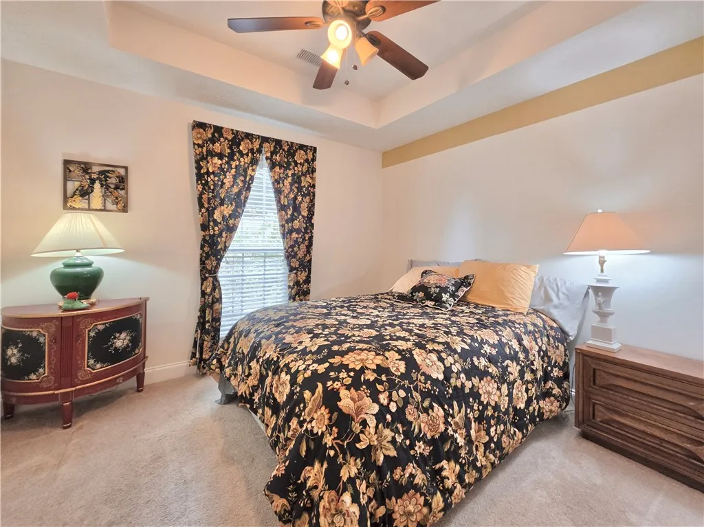 An elegant tray ceiling and soft wall-to-wall carpeting define this peaceful sleeping space.