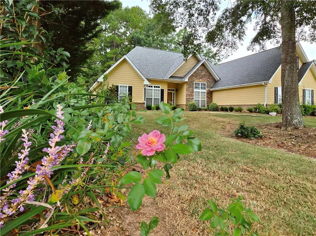 Mature trees and landscaping frame the gabled roofline and stone-accented facade of this charming residence.
