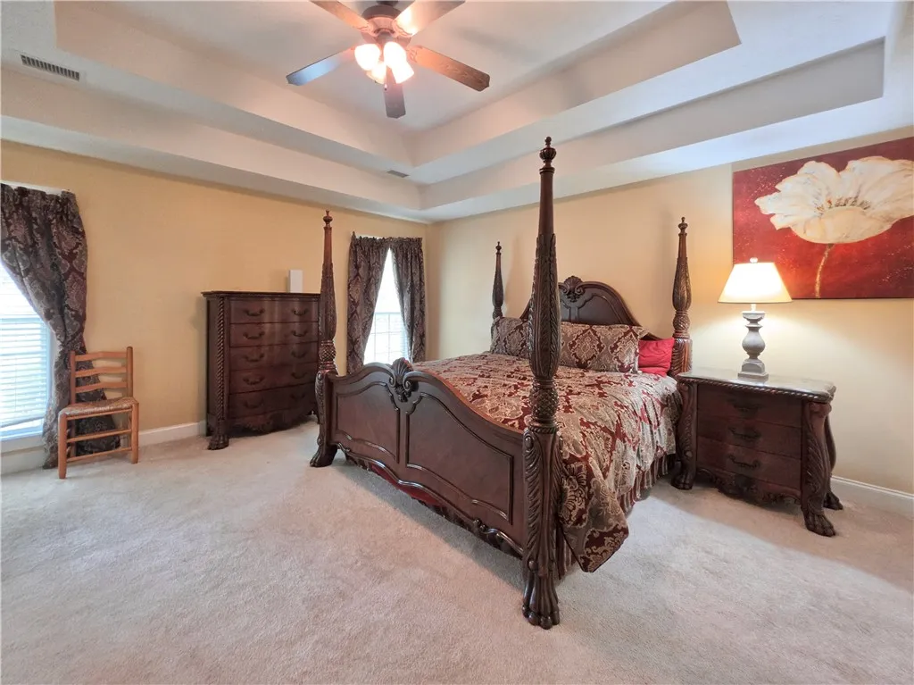 Multi-layered tray ceilings add architectural depth and elegance to this carpeted bedroom retreat.