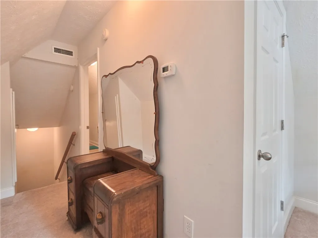 A classic staircase leads up to a carpeted upper landing with sloped ceilings.
