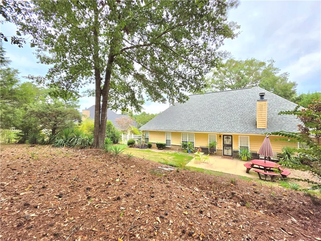 Mature trees frame the back yard and patio area of this traditional residence.