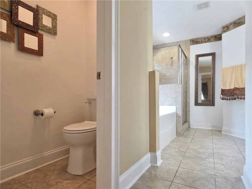 Crown molding highlights the high ceilings of this master bathroom with tile flooring.