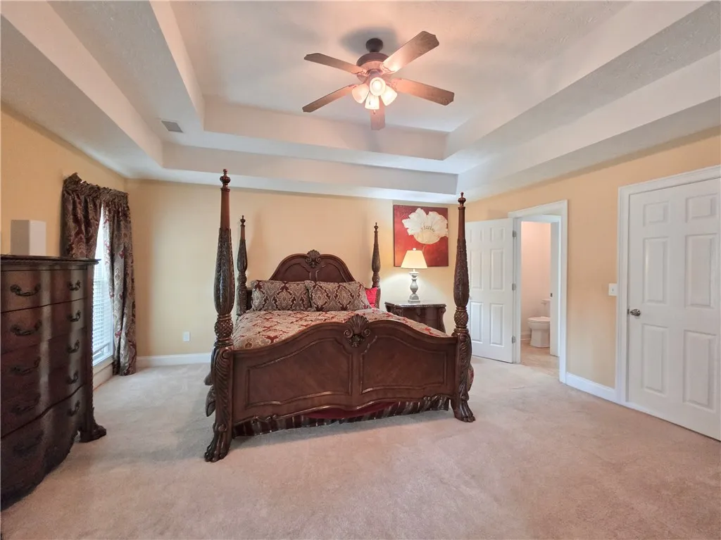 A tray ceiling highlights this bedroom complete with plush carpeting and an en-suite bath.