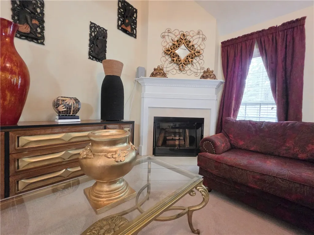 An elegant white fireplace anchors this comfortable living space featuring vaulted ceilings and soft carpeting.